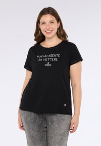 Maglietta nera a maniche corte con testo bianco e grafica di gruccia, scollatura rotonda e dettaglio sul lato. Il testo dice "NON HO NIENTE DA METTERE."