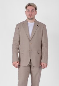 Completo in lino color beige chiaro con giacca a un bottone, due tasche frontali e pantaloni abbinati. Presenta bottoni marroni e una finitura testurizzata.