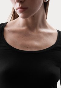 Zwarte, kortetermijn, crew-neck top met een gladde stof, met een close-up van de halslijn en het sleutelbeen, met minimale detailing.
