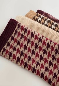 Trīs adītas zeķes ar suņu zobu rakstu burgundijas, bēšā un brūnā krāsā, ar strukturētām ribām uz augšējā malas.