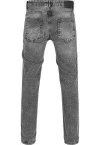 Vue arrière d'un jean en denim gris avec deux poches arrière, des détails cousus et un patch en cuir noir sur la ceinture.