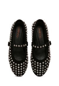 Zapatos planos Mary Jane negros con tachuelas redondas plateadas cubriendo la superficie y una correa con hebilla en la parte superior, etiquetados como DERIMOD en el interior.