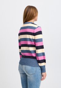 Pull-over rayé en rose, marine, crème et bleu. Doté d'un ourlet et de poignets côtelés. Texture douce, tricot de poids moyen, col rond.
