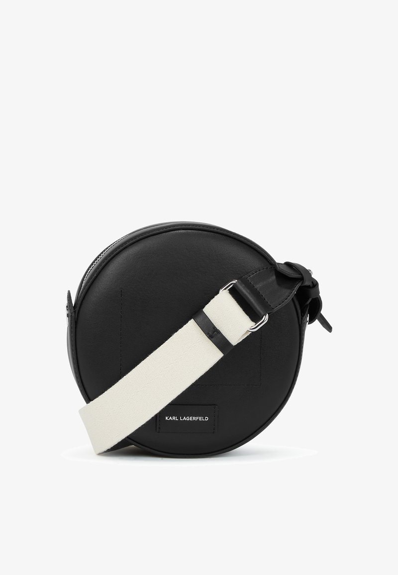 Round black leather crossbody bag with a white adjustable strap, featuring a smooth texture and embossed logo detail. Zipper closure.