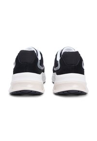 Αθλητικά παπούτσια μαύρου και λευκού χρώματος με υλικά από δίχτυ και σουέτ, στρογγυλεμένη φόρμα, επενδεδυμένους γιακάδες και υφή στη μαλακή, απορροφητική σόλα.