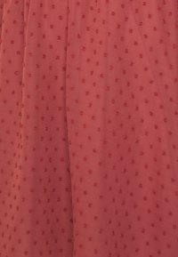 Roter Textilstoff mit erhabenem Punktmuster, der eine glatte Oberfläche und einen sanften Fall zeigt. Geeignet für verschiedene Bekleidungsstile.