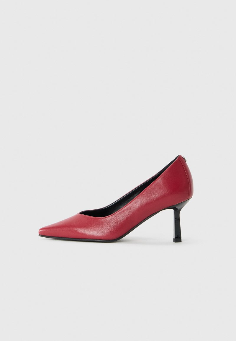 Czerwone skórzane szpilki z wysmukłym noskiem i cienkim czarnym obcasem. Gładka faktura i elegancka sylwetka.
