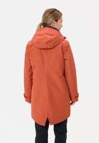 Giacca impermeabile arancione con cappuccio, caratterizzata da un design di lunghezza media e polsini regolabili, realizzata in un materiale liscio e texture.
