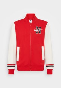 Chaqueta roja con cremallera y mangas blancas, con una "N" negra y el logo de Nike. Incluye bolsillos laterales y detalles a rayas en los puños. Mezcla de algodón.