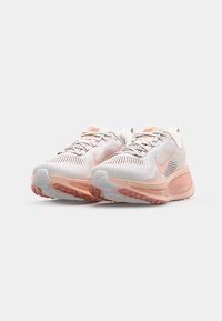 Scarpe da corsa Nike in bianco e rosa pallido, con tomaia in rete, colletto imbottito, suola ammortizzata e suola in gomma testurizzata.