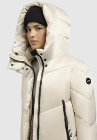 Puffervest i hvid med høj krave, lynlåslommer og logo patch. Har hætte og quiltet tekstur for varme.