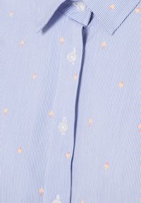 Camicia a righe blu chiaro e bianche con piccoli motivi di coni gelato gialli e rossi, con chiusura a bottoni e colletto a punta.