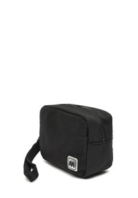 Čierna kozmetická taštička so zipsom, obdĺžnikového tvaru, s textúrovanou látkou a bočným uchom. Na prednej strane sa nachádza branding v striebornom štvorci.