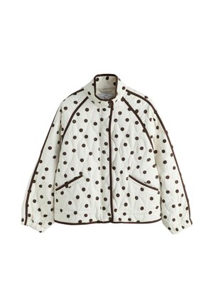 Balta krāsā ar brūniem polka punktiem šūta jaka ar augstu apkakli, priekšā ar rāvējslēdzēju un divām sānu kabatām ar brūnu apmali.