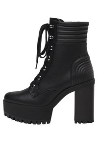 Stivaletto nero realizzato in ecopelle, con una suola piatta spessa, cuciture in rilievo, allacciatura frontale e tacco rotondo chunky.