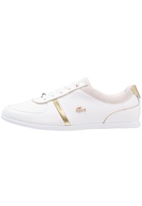 Bílá atletická obuv se zlatými doplňky, s texturovanými panely, zavazováním na tkaničky a plochou podrážkou; logo na boku, prodyšný síťovaný svršek u jazyka.