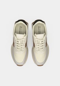 Βίγκαν αθλητικά παπούτσια σε εκρού και καφέ χρώμα με απαλή υφή, διακοσμημένα με στρογγυλεμένη μύτη, κορδόνια και ελαστική σόλα. Διακοσμημένα με μαύρο στο πίσω μέρος.