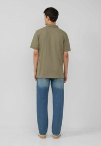 Khaki Poloshirt mit kurzen Ärmeln, kombiniert mit hellblauen, leicht verwaschenen Jeans. Glatte Textur, klassische Passform und lässiger Stil.