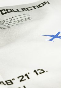 White fabric featuring black text with coordinates and a blue airplane graphic. Text includes "COLLECTION" in bold font above the graphic.