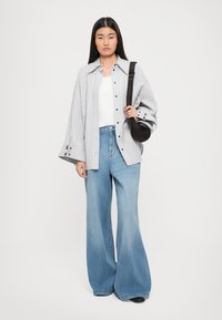 Striped oversized button-up shirt in gray and white, paired with light blue wide-leg jeans. Accessories include a small black crossbody bag.