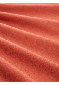 Zachte, rekbare stof in een gedempte koraalkleur met een gladde textuur, voorzien van subtiele plooien en zachte draping.