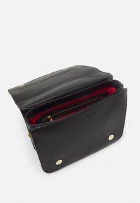 Černá kožená crossbody taška Love Moschino otevřená, ukazující červenou textilní výstelku a zipovou kapsu, se zlatými kovovými západkami.