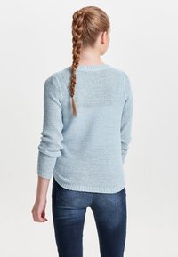 Lichtblauwe gebreide trui met middellange mouwen, ronde halslijn en geribbelde onderkant. Gestructureerd materiaal met een losse pasvorm.