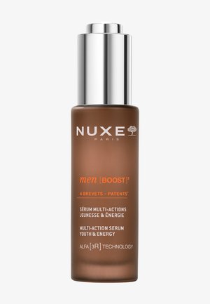 Bruine glazen fles met een metallic zilveren pompdeksel. Het bevat witte en oranje tekst, die een multi-actieve serum voor mannen van Nuxe Paris aangeeft.