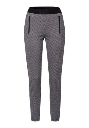 Zwart-witte sportbroek met patroon, voorzien van een brede zwarte tailleband, twee ritssluitingen en rode accenten aan de zijkanten. Strak ontwerp met taps toelopende benen.
