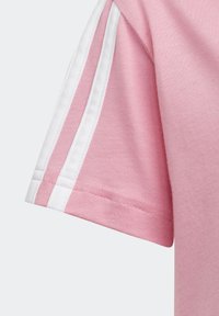 Różowa koszulka z krótkim rękawem z białymi paskami wzdłóż rękawów; wykonana z miękkiej bawełny o gładkiej fakturze i starannym przeszyciu.