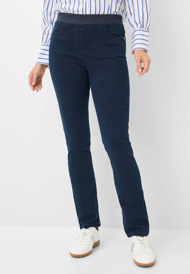 Pantaloni stretch navy con una texture liscia, vita elastica e due tasche frontali. Abbinati a sneakers bianche per un look casual.
