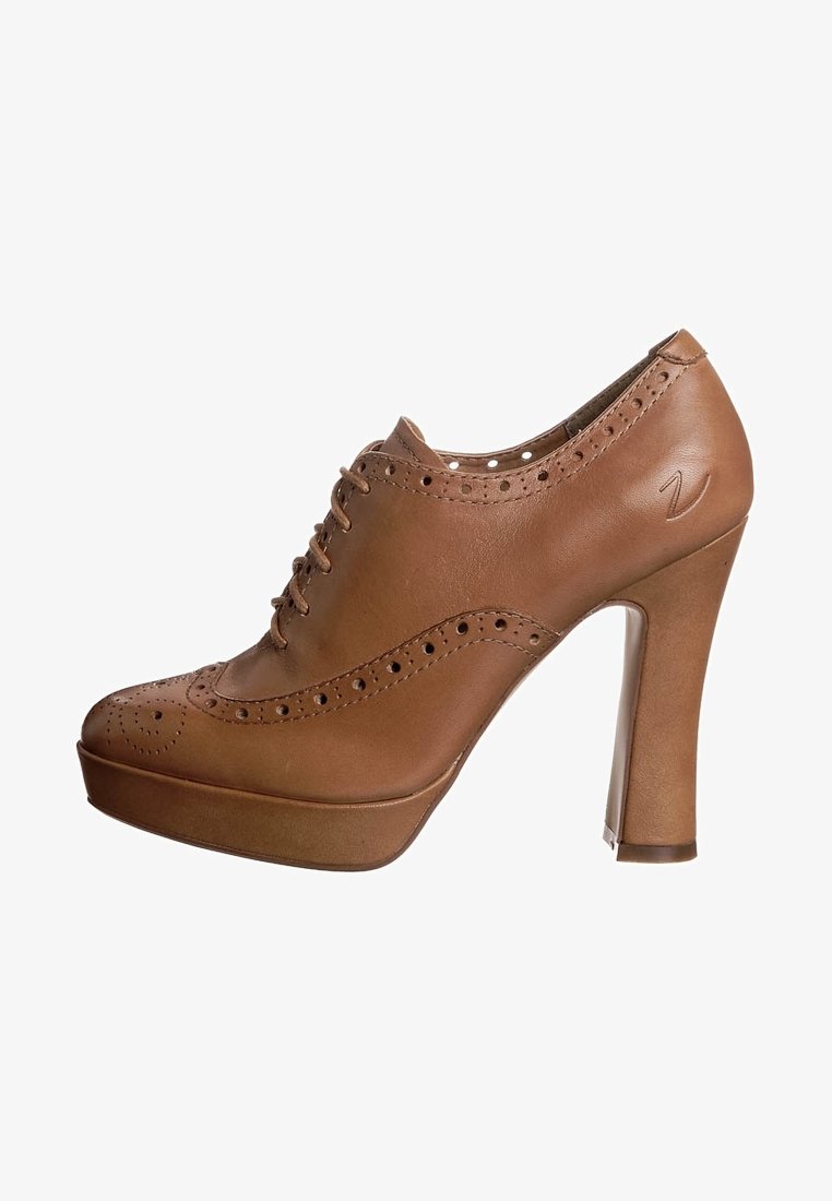Chaussure haute en cuir marron avec un bout arrondi, des détails perforés et une base plateforme. Présente un laçage et un talon transparent.