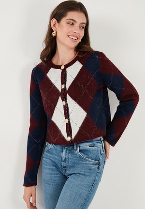 Cardigan in burgundy, navy, and cream featuring a diamond pattern, round neckline, and gold buttons. Long sleeves with relaxed fit.