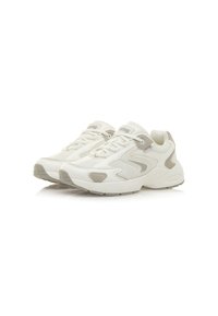 Zapatillas deportivas blancas con una parte superior de cuero texturizado y malla, con sutiles acentos en color beige y una suela acolchada con forma redondeada.