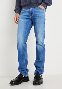 Blugi din denim albastru cu o croi dreaptă, textură decolorată și detalii subtile de frecare. Asortați cu pantofi loafer negri.