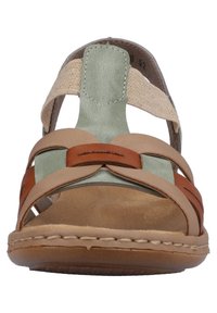 Sandale en cuir brun et beige avec des accents verts, design ouvert, brides tissées et coutures le long de la semelle. Semelle plate.
