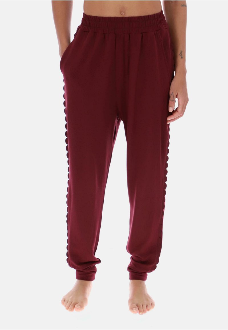 Burgunderfarvede joggingbukser med elastisk talje, sidelommer og bølget kantdetail langs siderne. Fremstillet af blødt, glat stof.