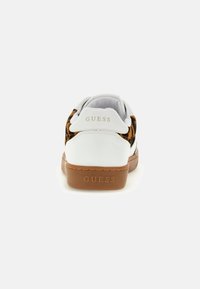 Sneaker bianco con dettagli in stampa animale, suola marrone e logo del brand in oro goffrato sul tallone, caratterizzata da un design in pelle liscia e tessuto testurizzato.