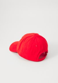 Rode katoenen baseballpet met een gebogen rand, verstelbare band aan de achterkant en geborduurde oogjes voor ventilatie.