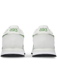 Vita sneakers med gröna accenter, med en stilren design, texturerat material och gummisula. "Asics" logotyp på hälen.