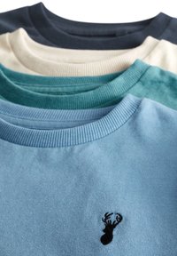 Vier gefaltete Rundhalspullover in Navy, Creme, Blaugrün und Hellblau mit einem schwarzen bestickten Hirschkopf auf dem hellblauen Pullover.