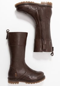 Brązowe skórzane kozaki do kolan z ozdobnymi perforacjami, bocznym zamkiem błyskawicznym i pętelką do ściągania. Gruba podeszwa z teksturowanym bieżnikiem zapewniającym przyczepność.