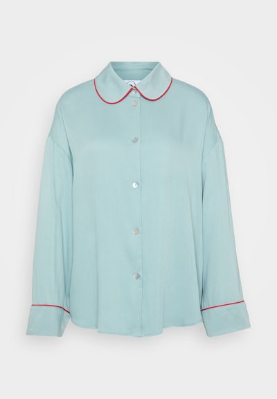 Šviesiai mėlynas ilgo rankovėmis marškinis su apvaliu apykakle, raudonu apvadu ir mygtukų užsegimu. Minkšta tekstūra, laisvas siluetas ir platūs rankovės su apykaklės detaile.