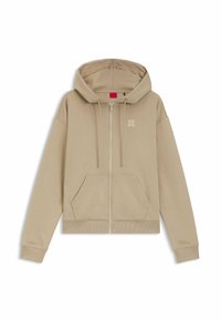 Beige Kapuzenpullover mit Reißverschluss, Fronttaschen, Kordelzug an der Kapuze, gerippten Bündchen und Saum sowie kleinem "HUGO"-Logo auf der linken Brust.