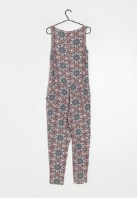 Combinaison imprimée à design sans manches, avec un col rond, ornée de motifs floraux complexes dans des tons de bleu, blanc et rose. Accrochée à un crochet noir.