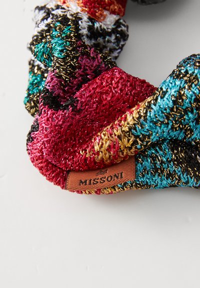 Gestrickte Haargummis in lebhaften Farben von Rot, Blau, Schwarz und Gold mit einem strukturierten metallischen Faden; versehen mit einem braunen Lederanhänger mit der Aufschrift "MISSONI."