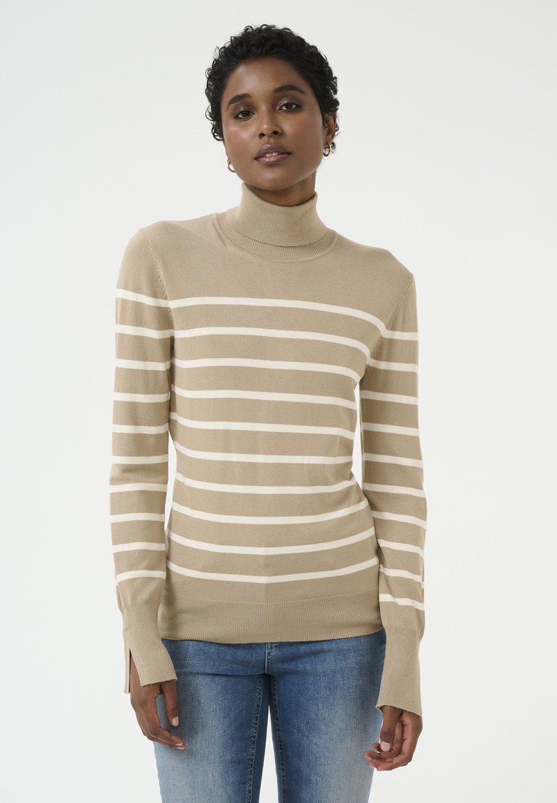 Kerman raidallinen turtleneck-neulepaita, jossa on kerma-valkoiset vaakaraidat, pitkät hihat, sivuaukot sekä sileä neulepinta. Yhdistettynä sinisiin farkkuihin.