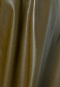 Olivengrön texturerad läder med en slät yta, som har synliga kornmönster och en subtil lyster. Tyget faller mjukt.