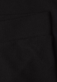 Tissu tricoté noir avec texture côtelée présentant une partie pliée créant une couture ombrée.