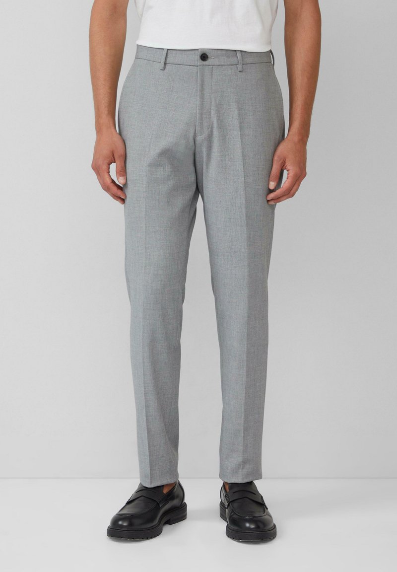 Grijze op maat gemaakte broek met een subtiele textuur, voorzien van een enkele knoopsluiting, zijzakken en een slim fit. Draagt een paar zwarte dresschoenen.
